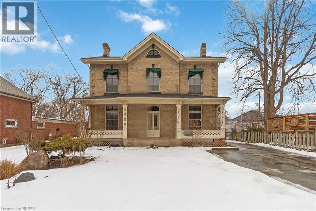 A large, two-story house with a porch and a snow-covered front yard.