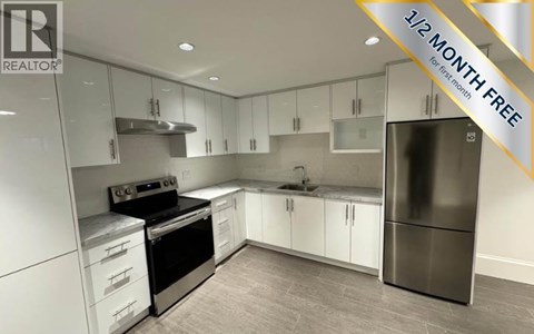 A modern kitchen with a stainless steel refrigerator and white cabinets.