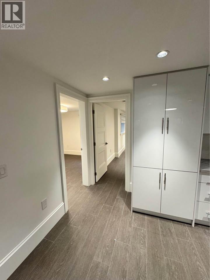 A white cabinet with two doors and two drawers is in the foreground of a room with a grey floor and white walls.