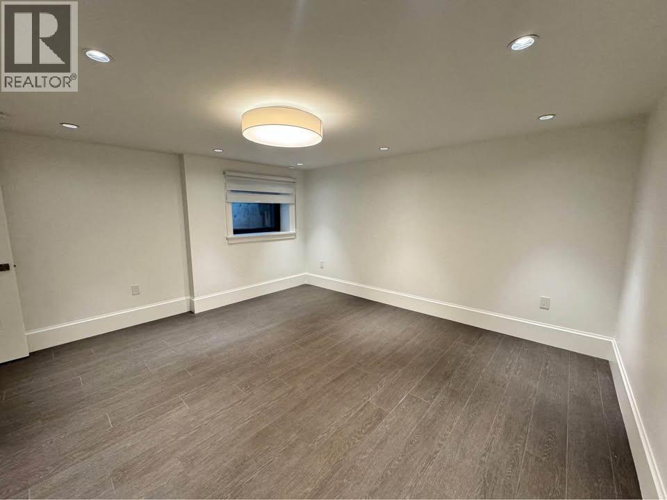 A spacious room with wooden flooring and a window.