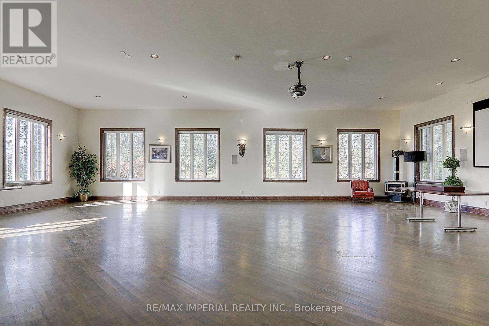 A spacious room with wooden floors and large windows.