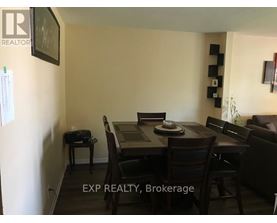 A dining room with a table set for two and chairs around it.