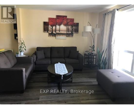A living room with a grey couch, a coffee table, and a painting on the wall.