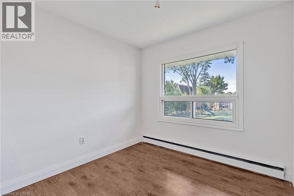 A room with a window showing a view of trees and houses outside.