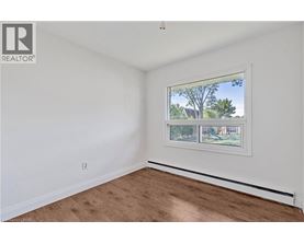 A room with a window showing a view of trees and houses outside.