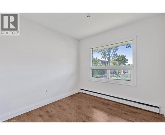 A room with a window showing a view of trees and houses outside.