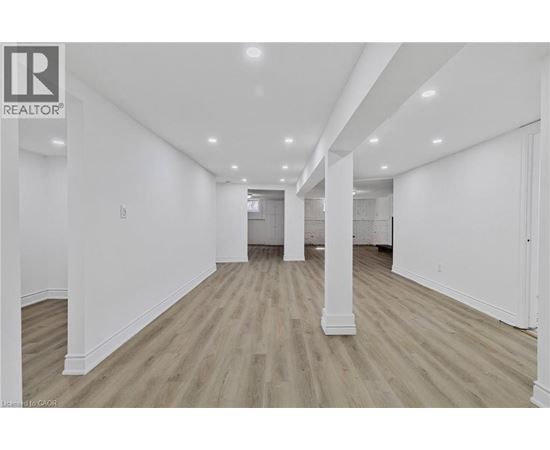 A spacious room with wooden flooring and white walls.