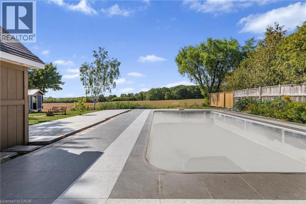 A swimming pool surrounded by a concrete deck and a wooden fence.
