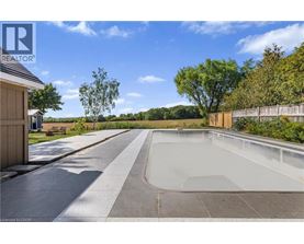A swimming pool surrounded by a concrete deck and a wooden fence.