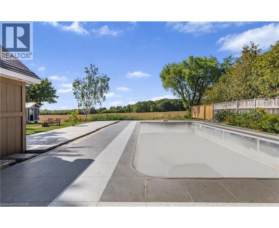 A swimming pool surrounded by a concrete deck and a wooden fence.