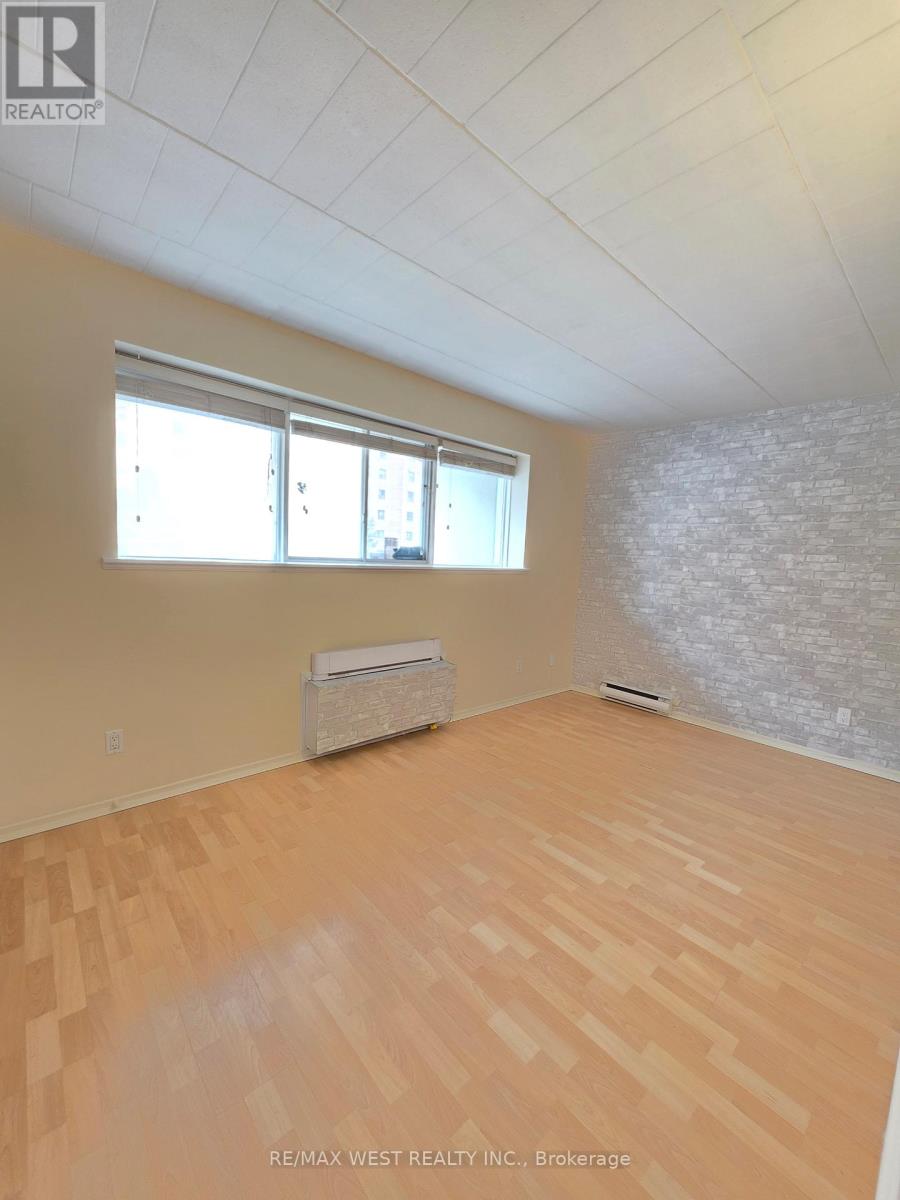 A room with wooden flooring and a window with blinds.