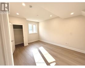 A spacious room with wooden flooring and a window letting in natural light.