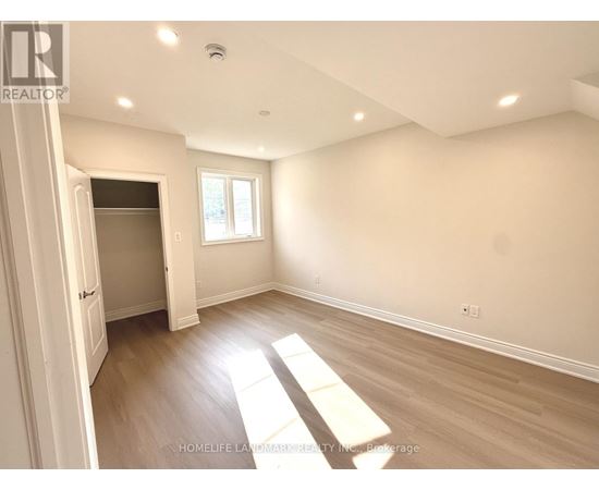 A spacious room with wooden flooring and a window letting in natural light.