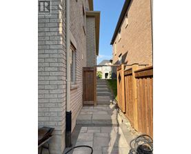 A narrow alleyway with a wooden fence on the right and a brick building on the left.