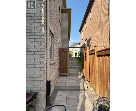 A narrow alleyway with a wooden fence on the right and a brick building on the left.