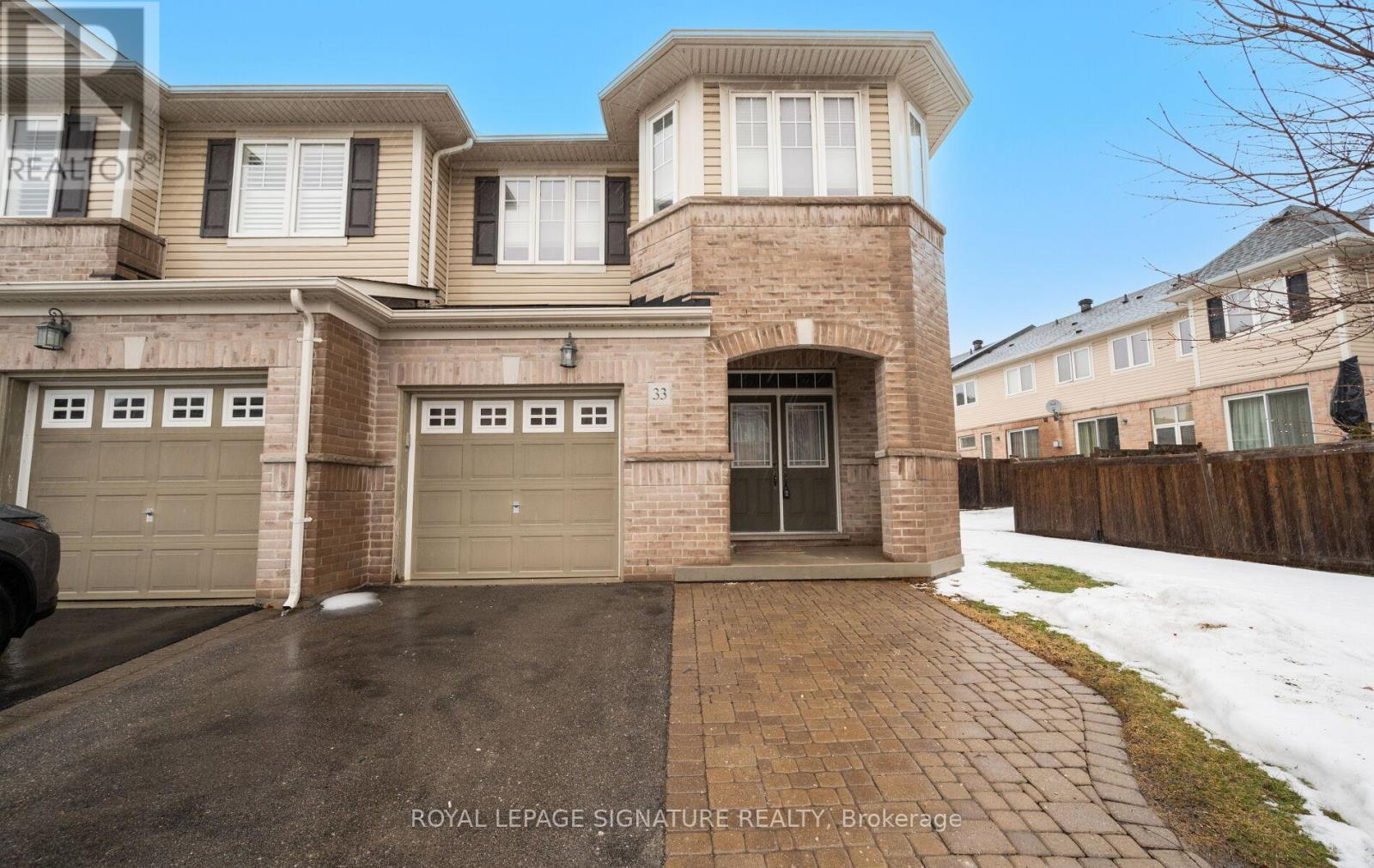 A large house with a brick facade and a garage is for sale.
