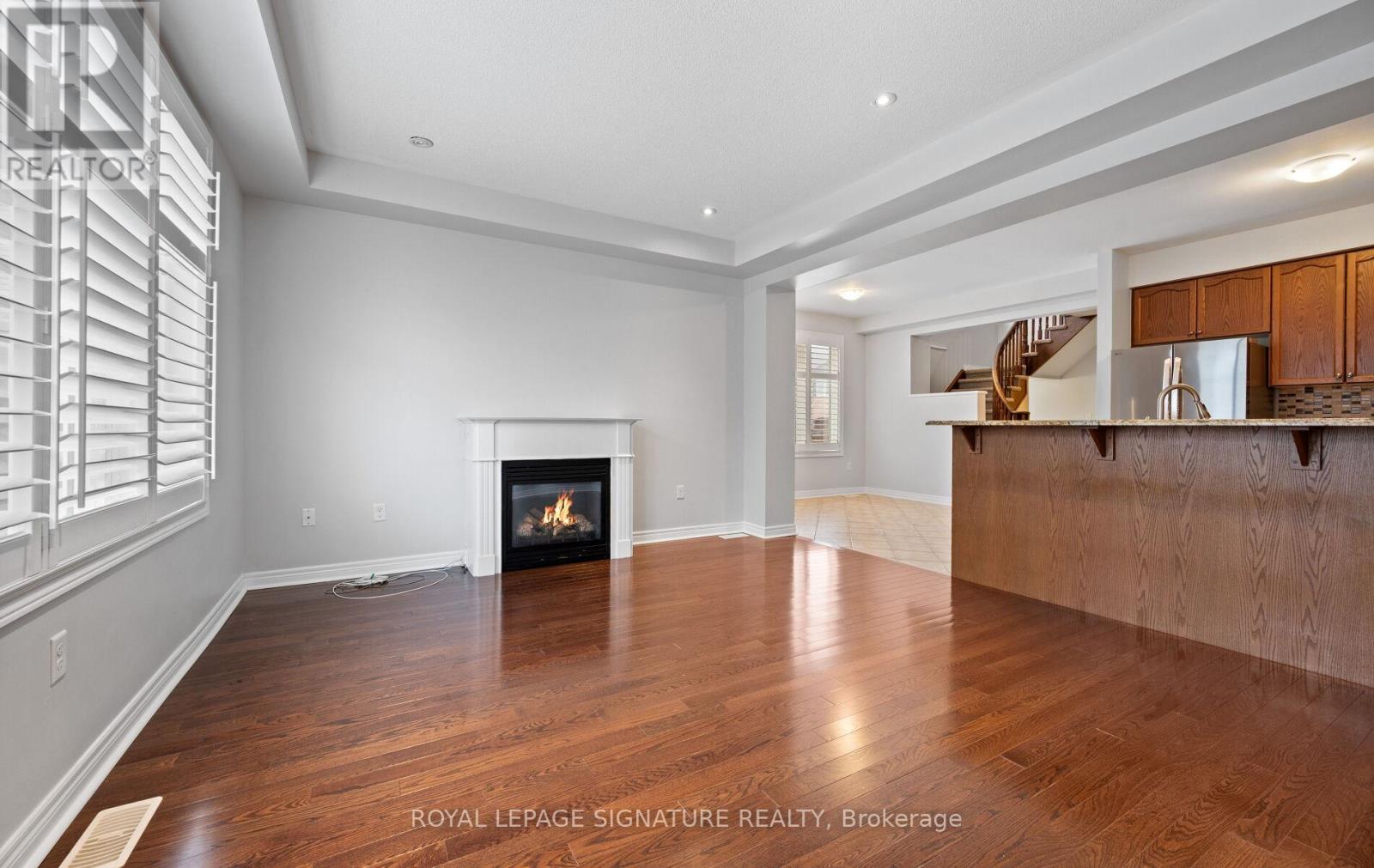 A spacious living room with a fireplace and wooden floors.