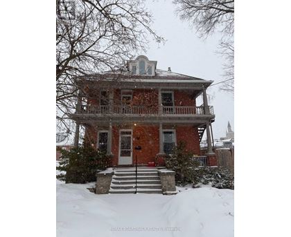 A red brick house with a balcony and a small tower on the roof.