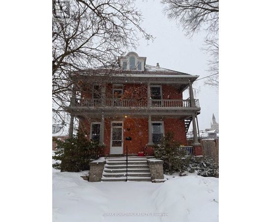 A red brick house with a balcony and a small tower on the roof.
