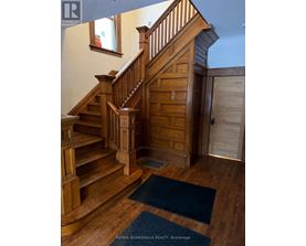 A wooden staircase with a blue rug in front of it.