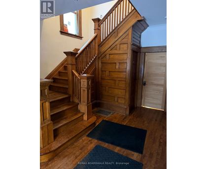 A wooden staircase with a blue rug in front of it.