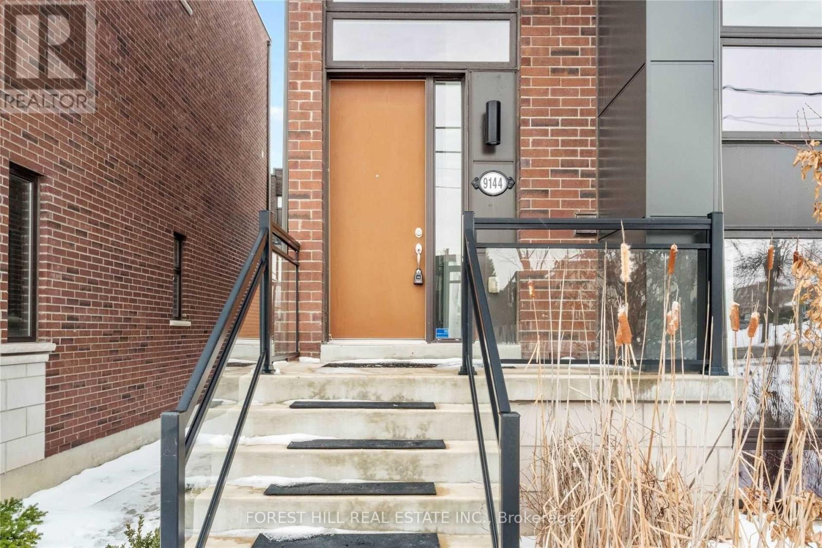 A brown door is on the right side of a brick building.