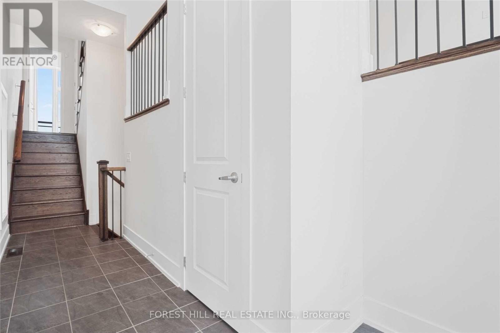 A hallway with a staircase and a white door.