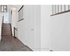 A hallway with a staircase and a white door.