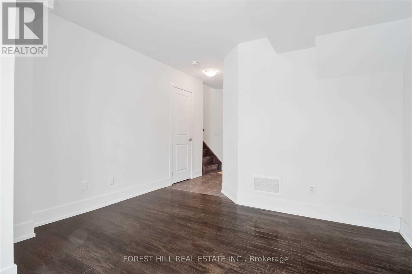 A spacious room with wooden floors and white walls.