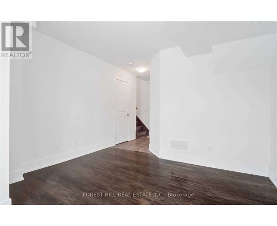 A spacious room with wooden floors and white walls.