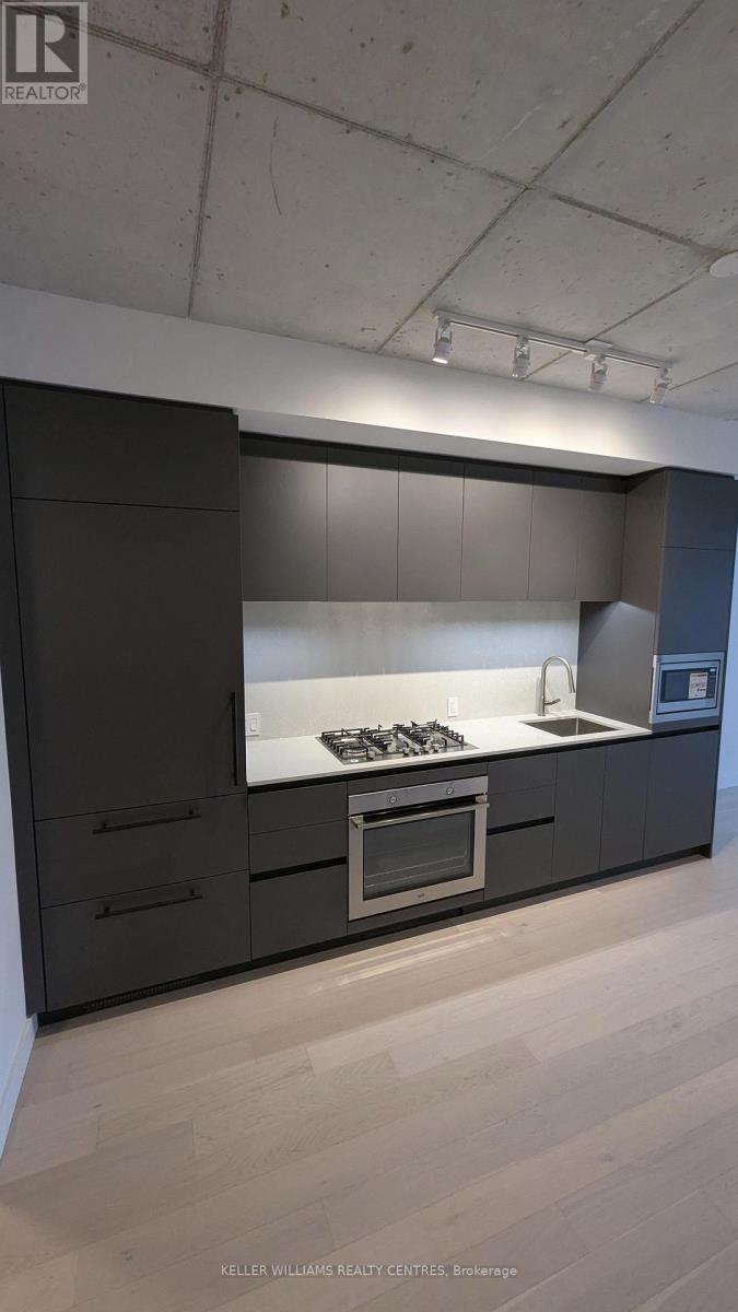 A modern kitchen with a stove top oven and a refrigerator.