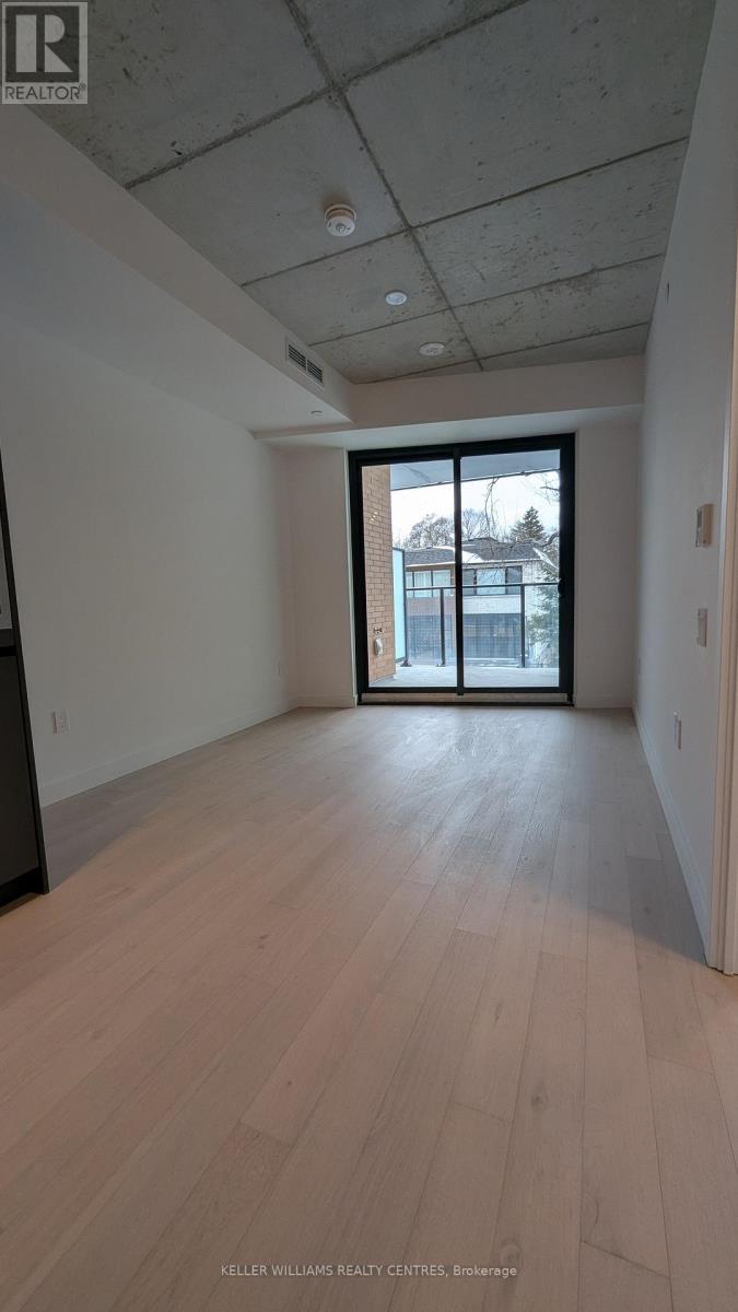 A spacious room with wooden flooring and a sliding glass door leading to a balcony.