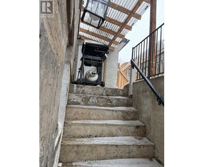 A staircase with a metal railing and a concrete wall.
