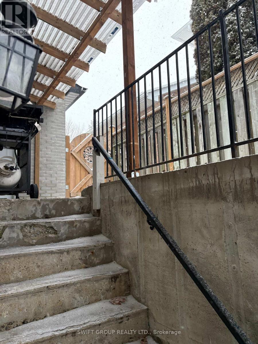 A staircase with a black railing and a white wall in the background.