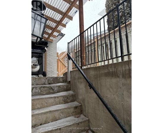 A staircase with a black railing and a white wall in the background.
