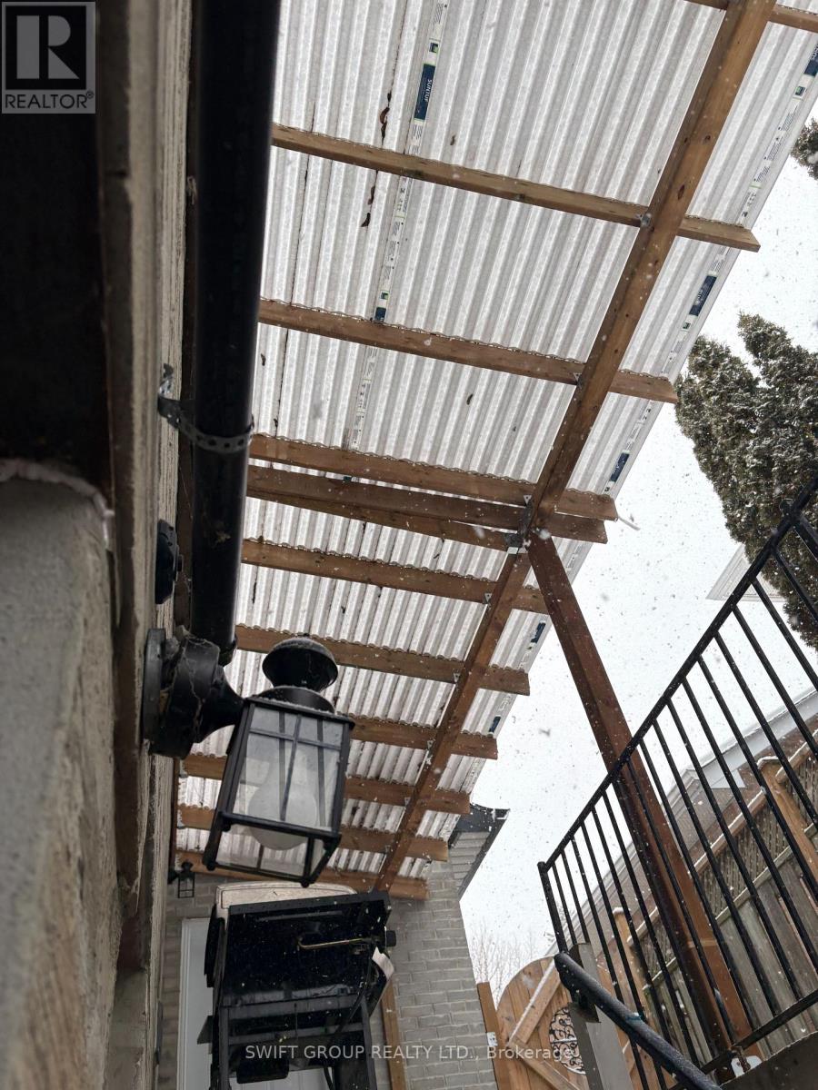 A corrugated metal roof with wooden beams and a black metal railing.