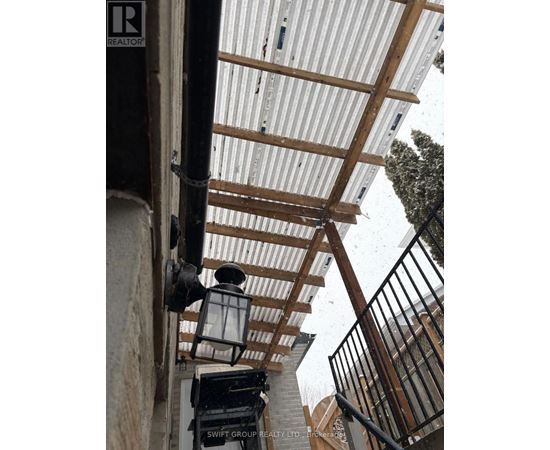 A corrugated metal roof with wooden beams and a black metal railing.