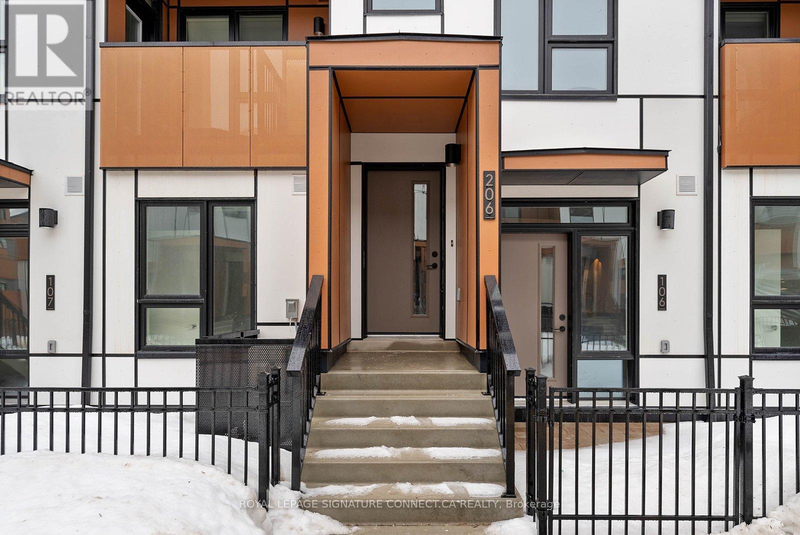A modern building with a black fence and a snowy ground.