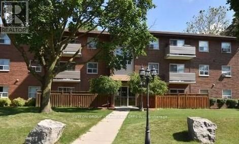 A brick apartment building with a green lawn in front.