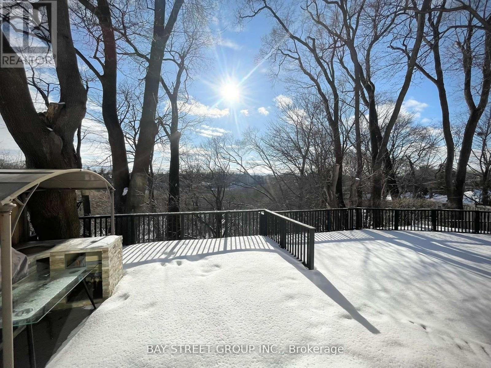 A snow-covered deck with a railing and trees in the background.