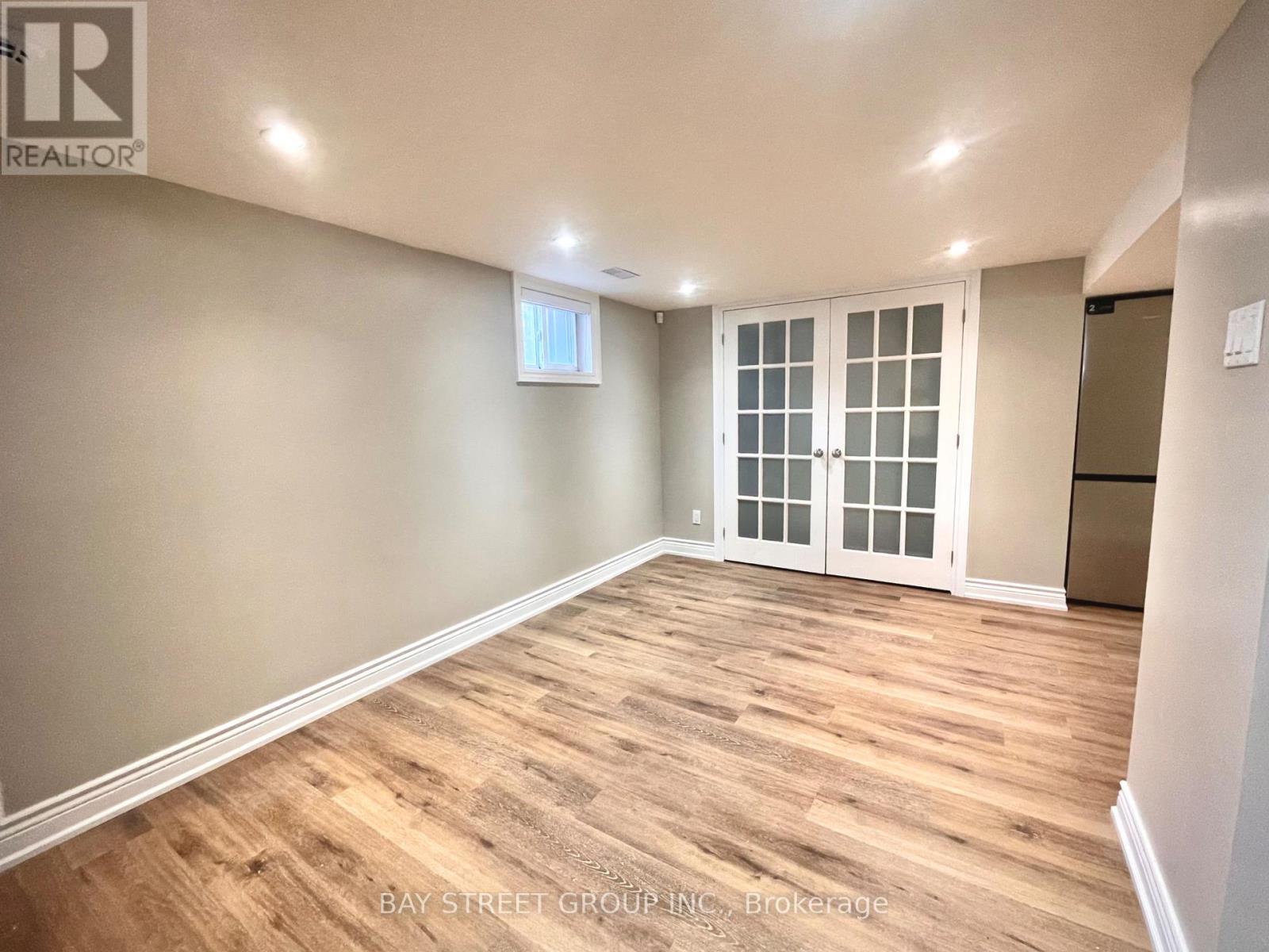 A spacious room with wooden flooring and a sliding glass door.