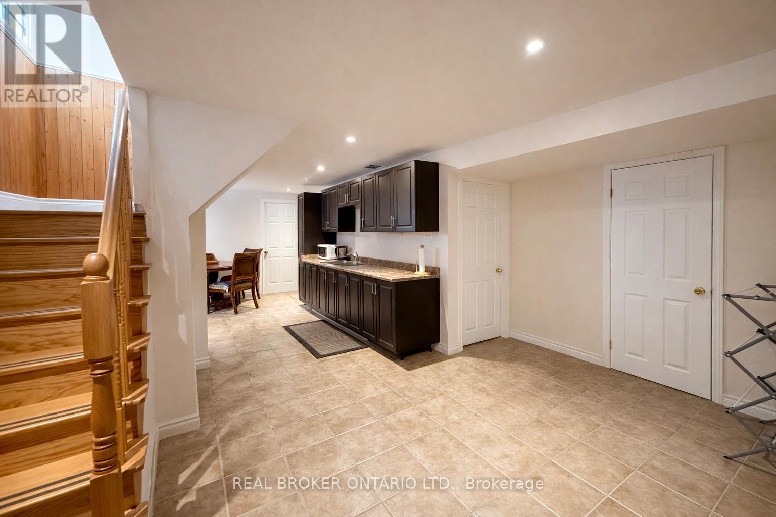 A spacious room with a bar area and a staircase.
