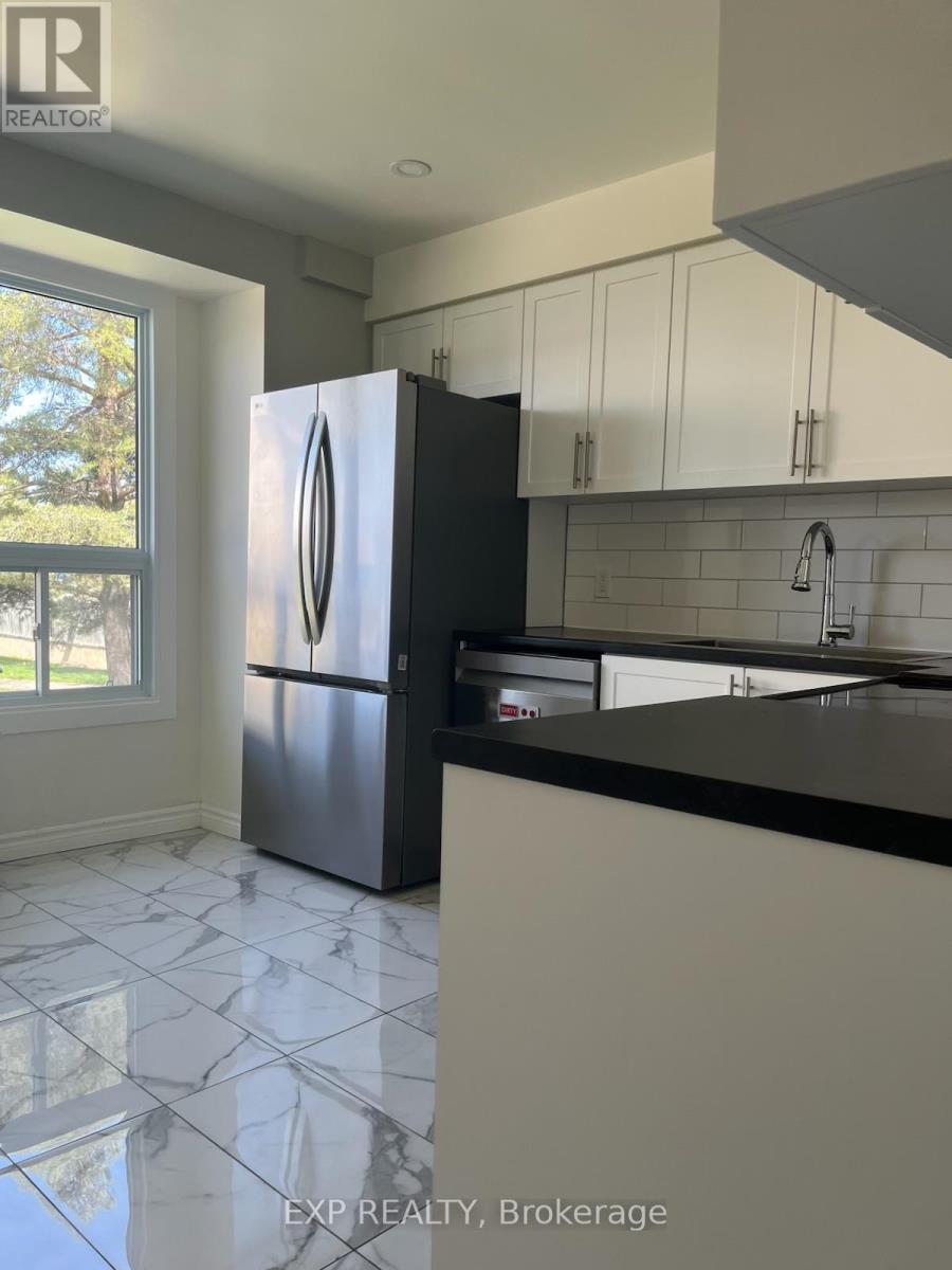 A kitchen with a black fridge and white cabinets.