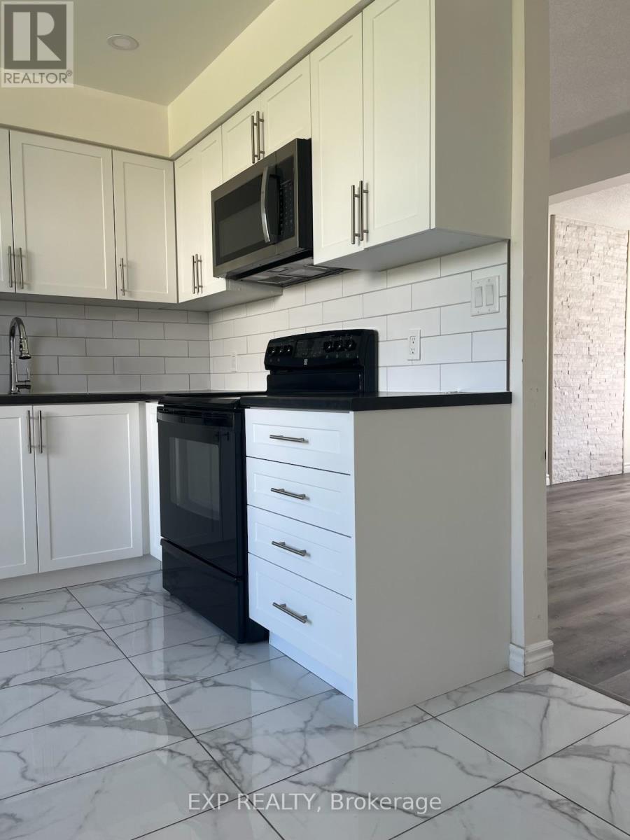 A kitchen with white cabinets and black appliances.