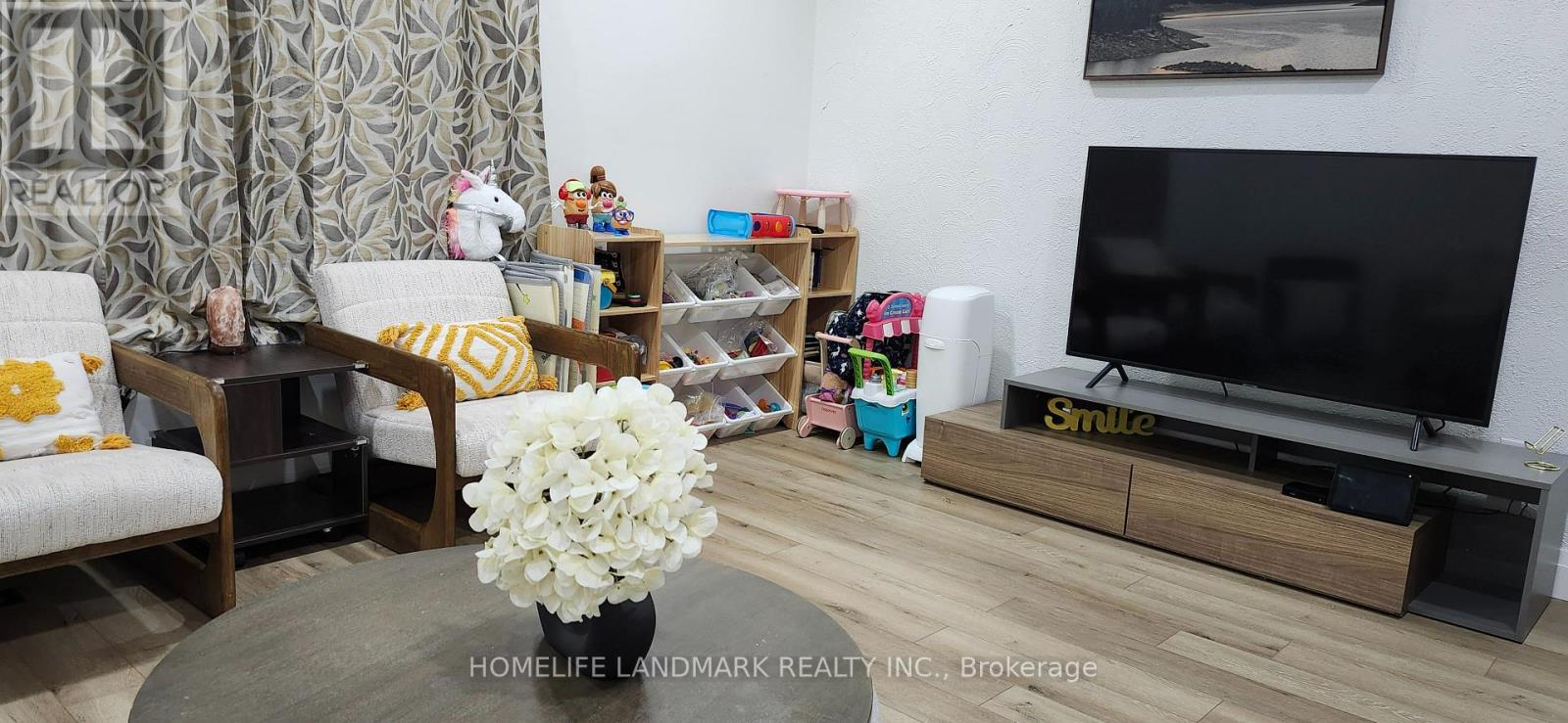 A living room with a flat screen TV and a coffee table with flowers on it.