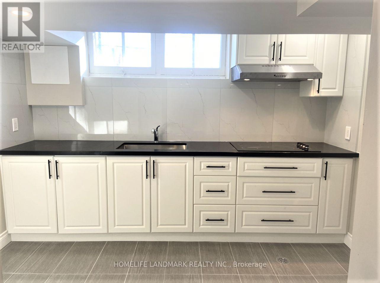 A kitchen with white cabinets and a black countertop.