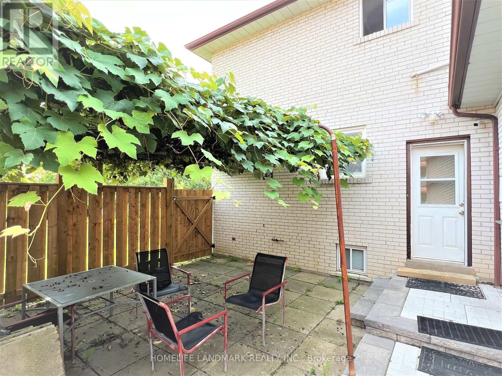 A patio with a table and chairs is covered in green vines.