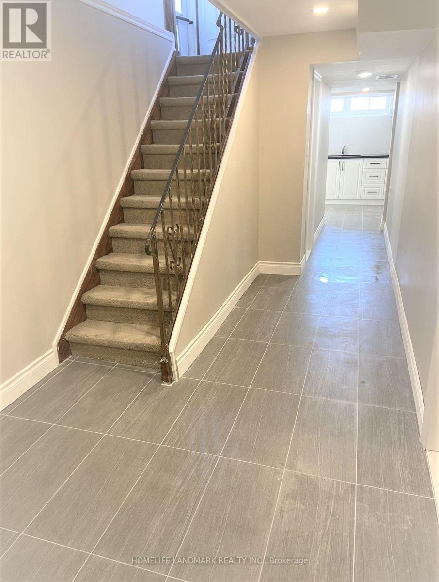 A hallway with a staircase and tiled flooring.