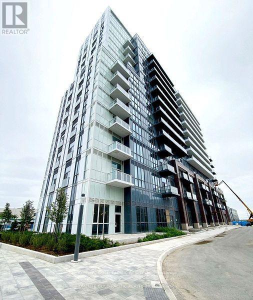 A modern glass building with a curved design and a cobblestone walkway in front.