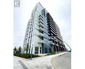 A modern glass building with a curved design and a cobblestone walkway in front.